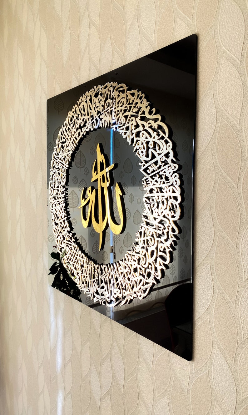 Decorative wall art with intricate design and gold text on a black background